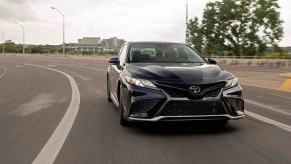 A black Toyota Camry, a rival for the Honda Accord, takes a corner at speed.