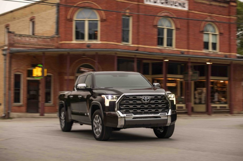 A brown Toyota Tundra drives past a brick building on an American main street.