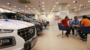 A row of Hyundai EVs parked inside a dealership, a table of customers speak with a salesperson in the background.