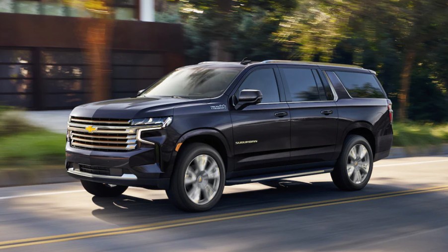 A blue 2023 Chevrolet Suburban is driving on the road.