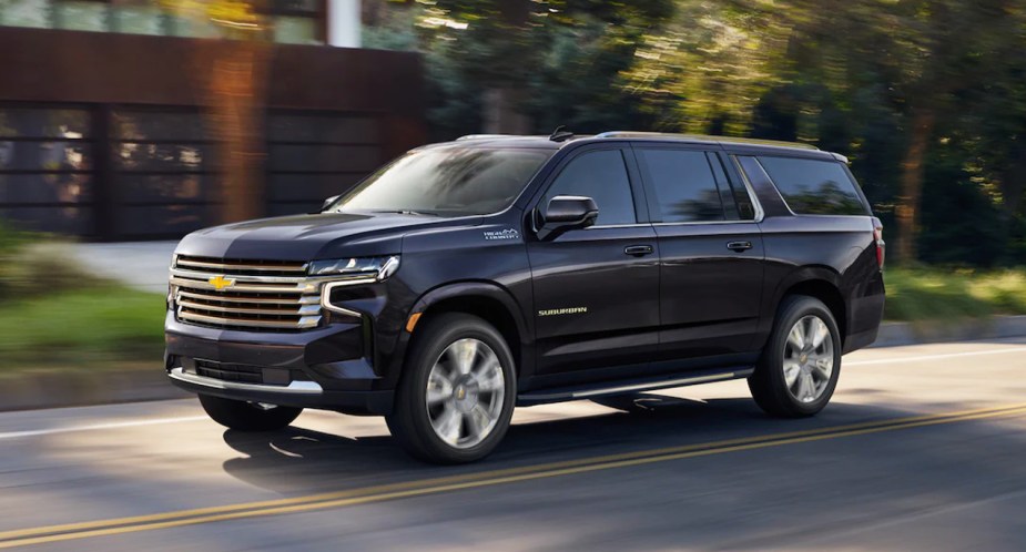 A blue 2023 Chevrolet Suburban is driving on the road. 