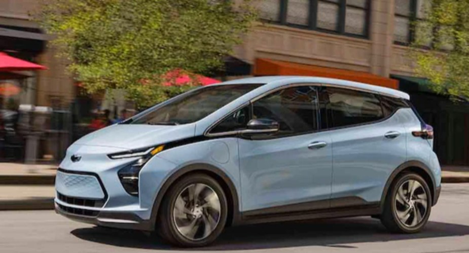A blue 2023 Chevy Bolt EV is driving on the road. 