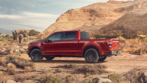 A red, entry-level Ford F-150 XL parked in the desert for a publicity photo, hikers visible in the background.