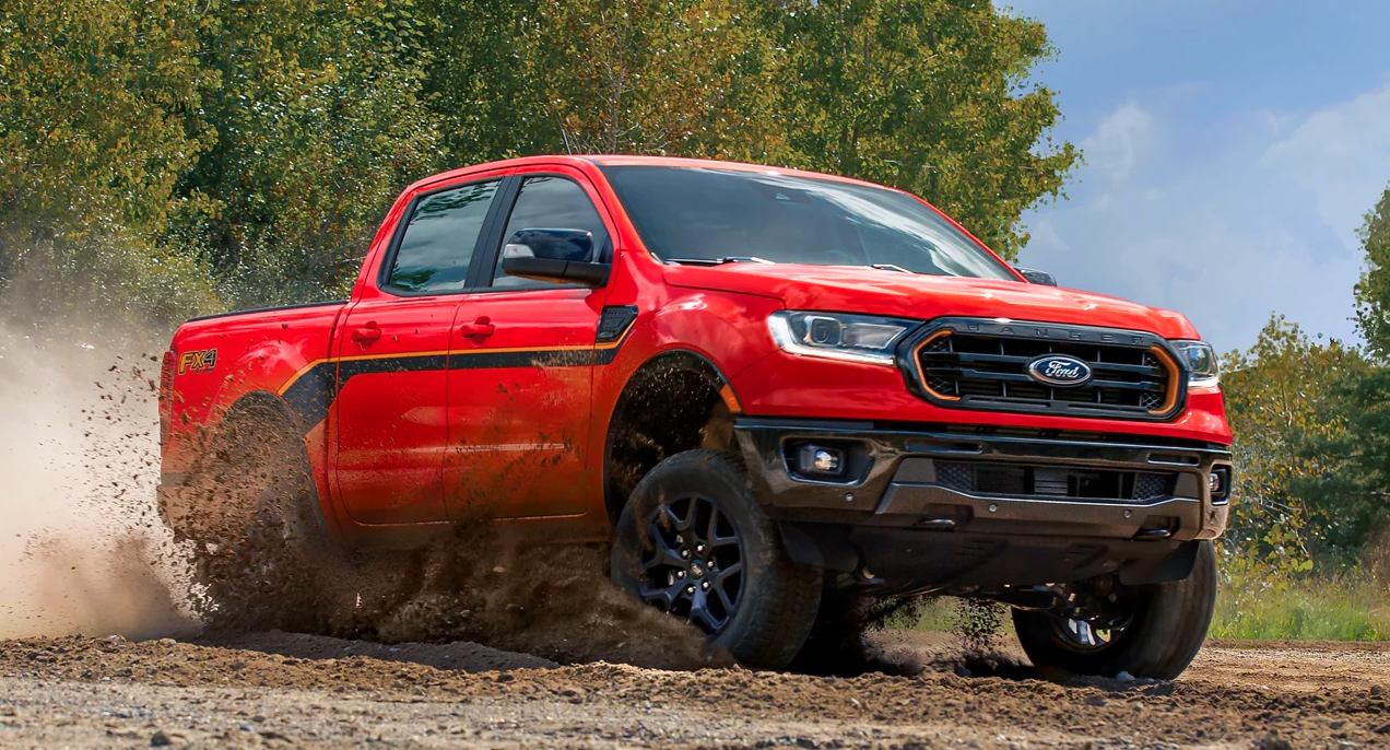 A red 2023 Ford Ranger midsize pickup truck is driving off-road.