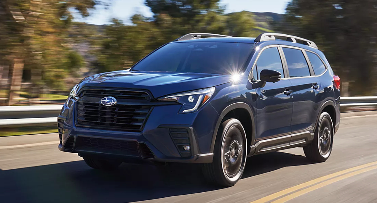 A blue 2023 Subaru Ascent midsize SUV is driving on the road.
