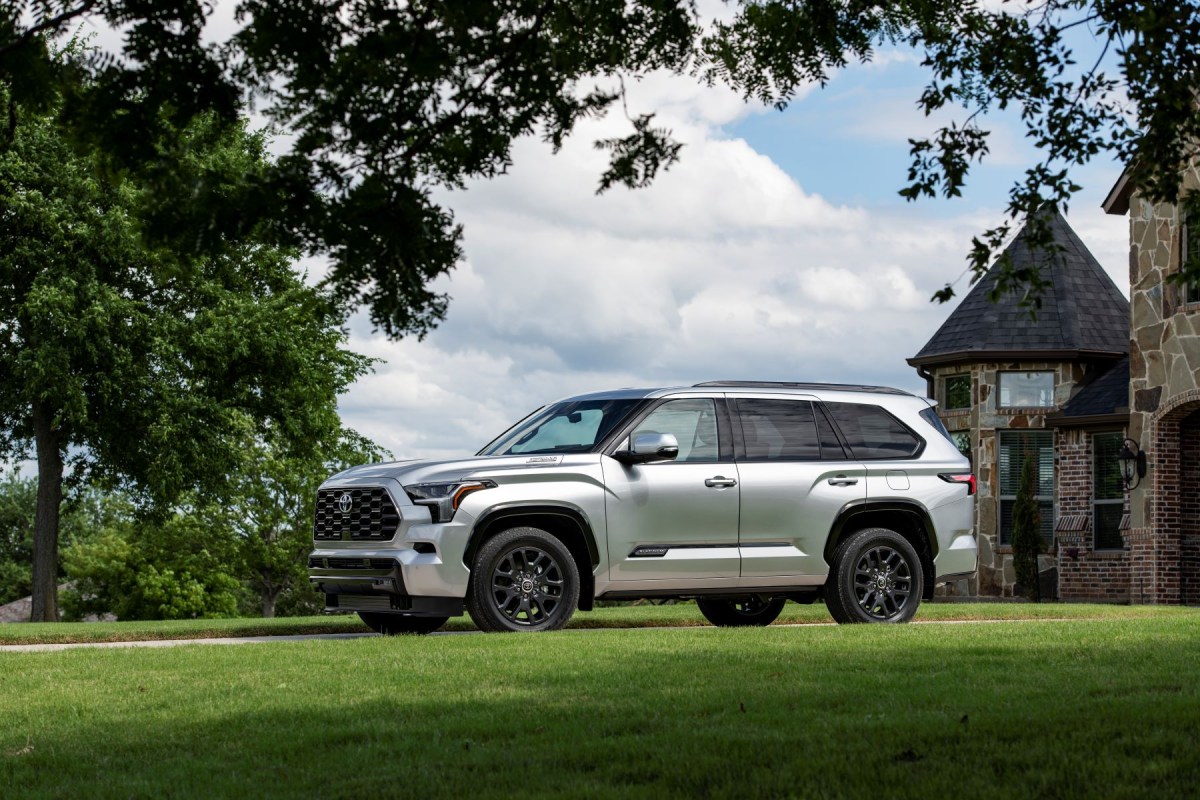 A 2023 Toyota Sequoia full-size SUV in Platinum Silver parked outside a luxury brick mansion. The Sequoia will finally have some inner-Toyota competition with the 2024 Grand Highlander.