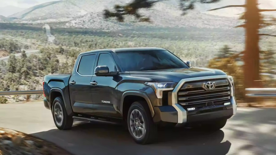 A black 2023 Toyota Tundra full-size pickup truck is driving on the road.