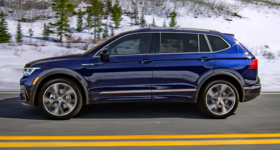 A blue 2023 Volkswagen Tiguan small SUV is driving on the road. 