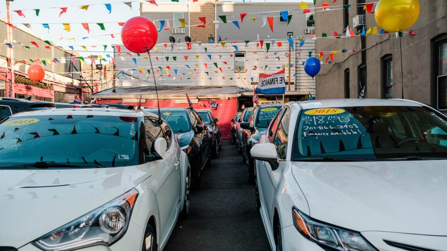 A car dealership with cars, balloons, and flag streamers that could have hidden fees.