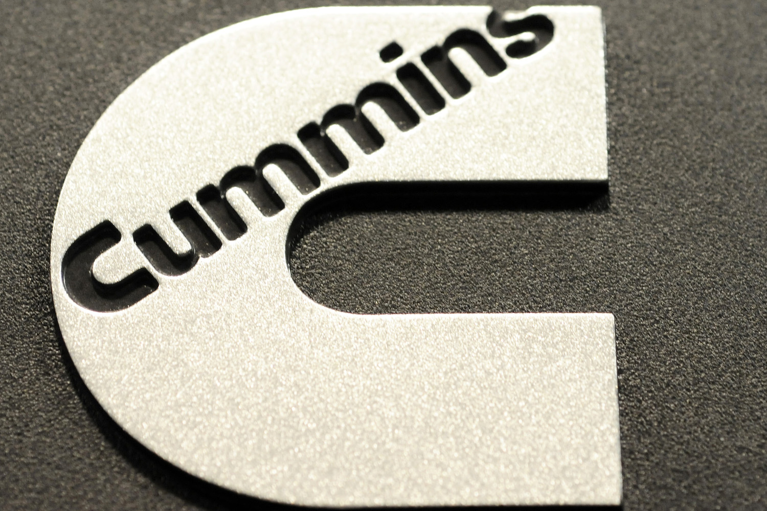 Closeup of a shiny Cummins logo at the company's Waterloo Indiana Army turbo diesel engine factory.