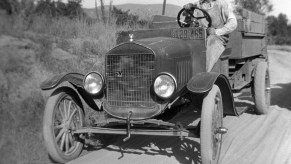 Black and white photo of a farmer driving a Ford Model TT truck on a sandy road.