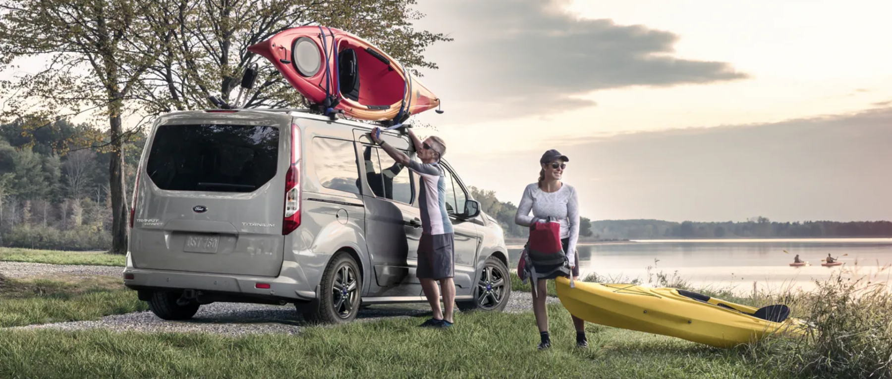 A 2022 Ford Transit Connect passenger wagon loaded up with kayaks near a lake