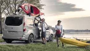 A 2022 Ford Transit Connect passenger wagon loaded up with kayaks near a lake