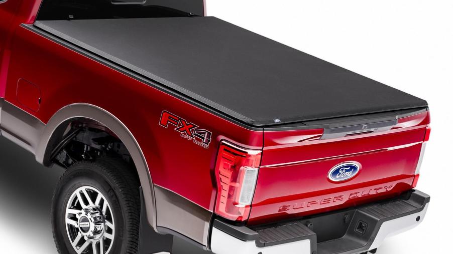 A red ford truck with a tonneau cover on the cargo bed. There are a few reasons to buy one.