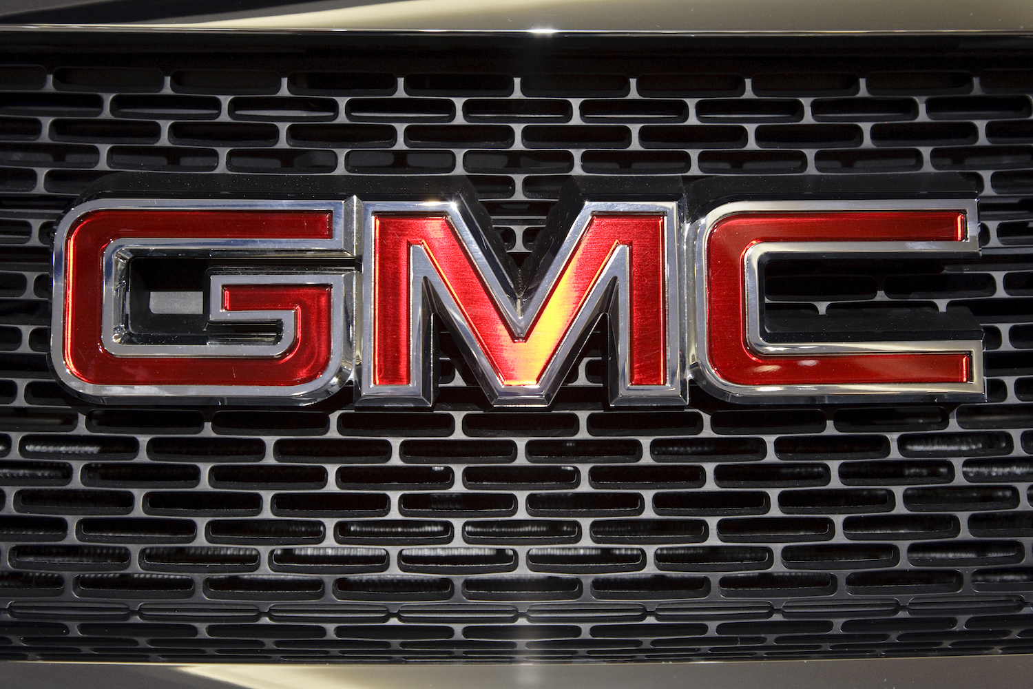 Closeup of a classic General Motors Company GMC logo on the grille of a truck at an auto show.