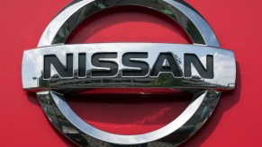 Nissan logo against a red background, makers of the Nissan model with the most reliability improvement.