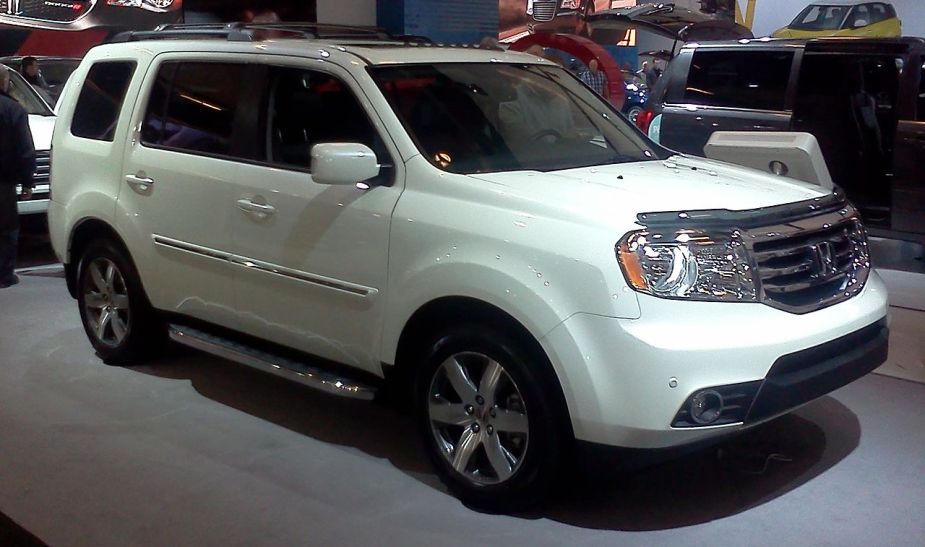 A white 2015 Honda Pilot SUV sits on display, it is a reliable used vehicle. 