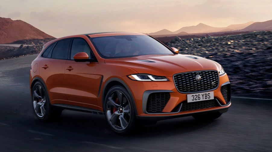 An orange Jaguar F-PACE is driving on the road.