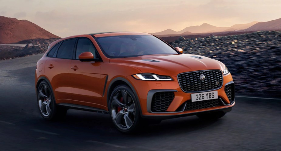 An orange 2022 Jaguar F-PACE is driving on the road. 