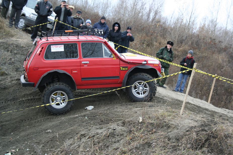 A red Lada Niva shows off its capability as a 4x4 SUV.