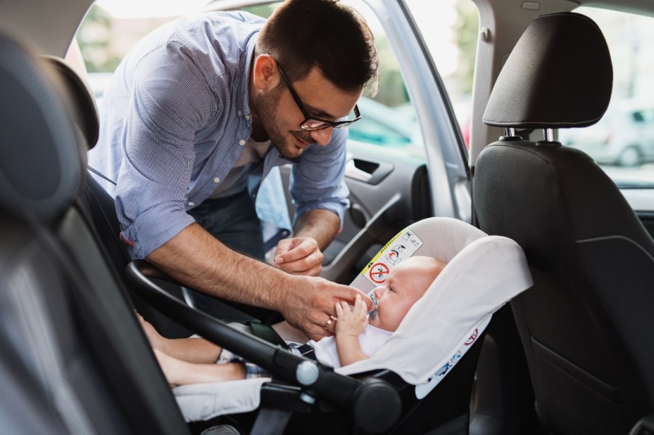 man putting baby in car seat