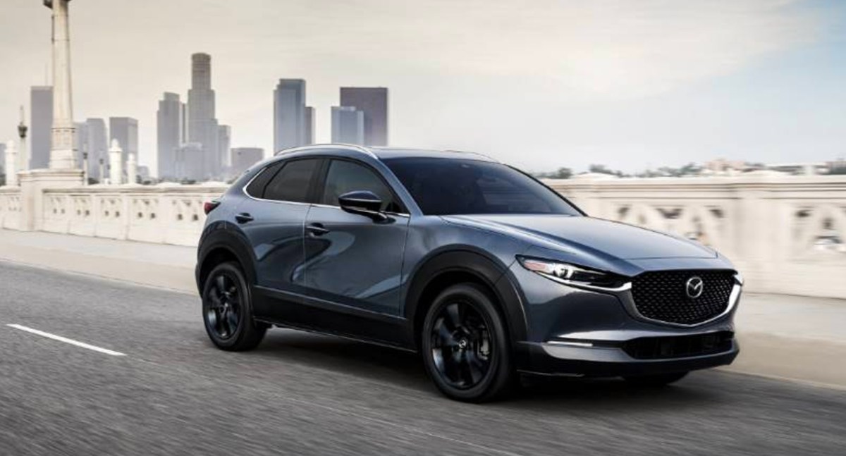 A blue Mazda CX-30 subcompact SUV is driving on the road.