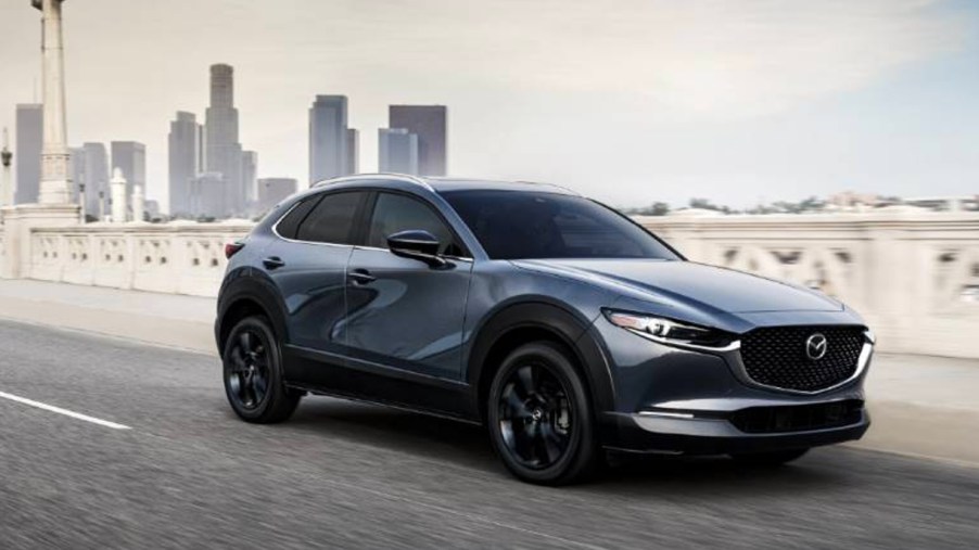 A blue Mazda CX-30 subcompact SUV is driving on the road.