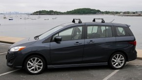 A Mazda 5 minivan sits in front of a body of water.