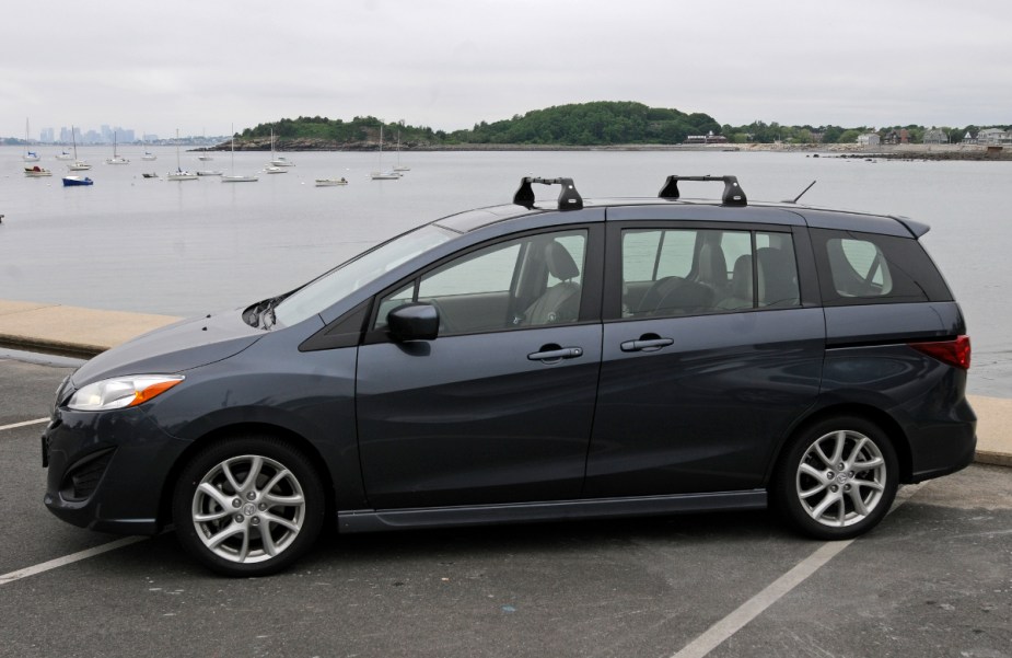 A Mazda 5 minivan sits in front of a body of water.