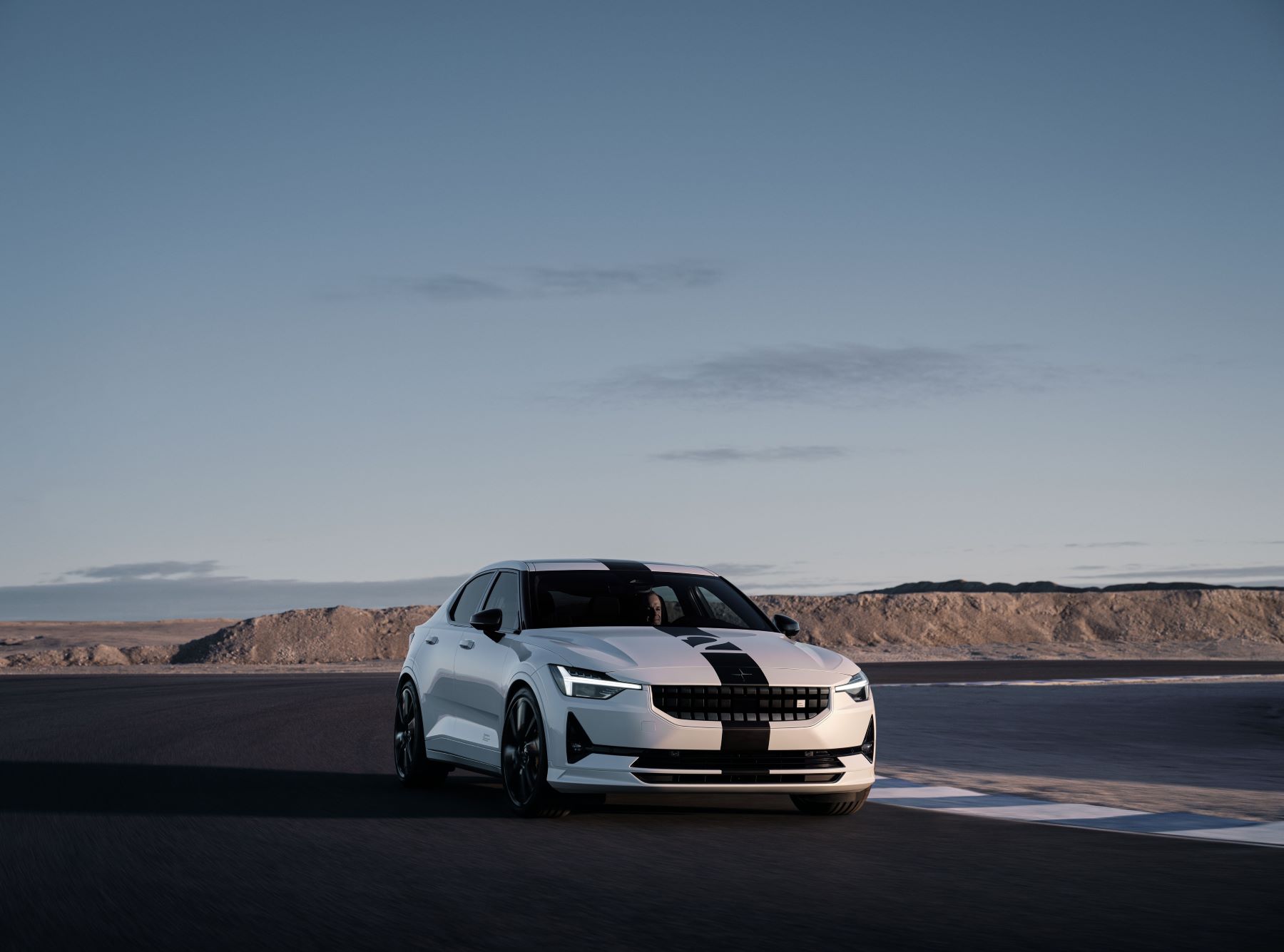 A white Polestar 2 BST Edition 270 electric muscle car model with a racing stripe on a race track