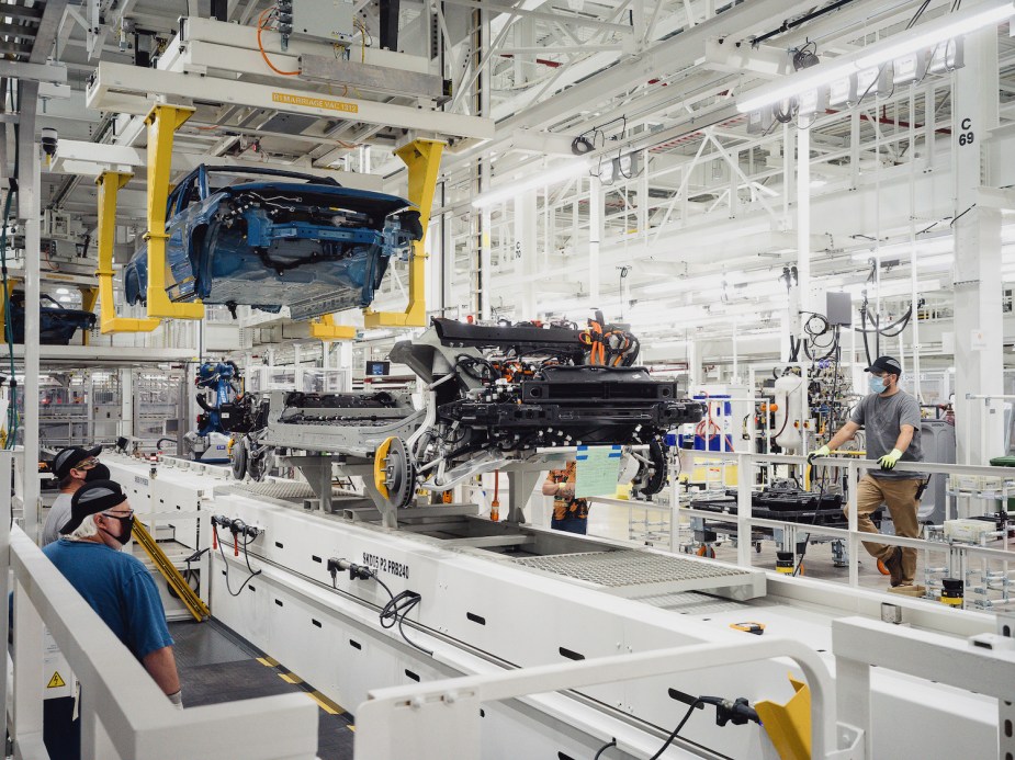 A Rivian R1T pickup truck body being lowered onto its electric EV skateboard chassis in a factory.