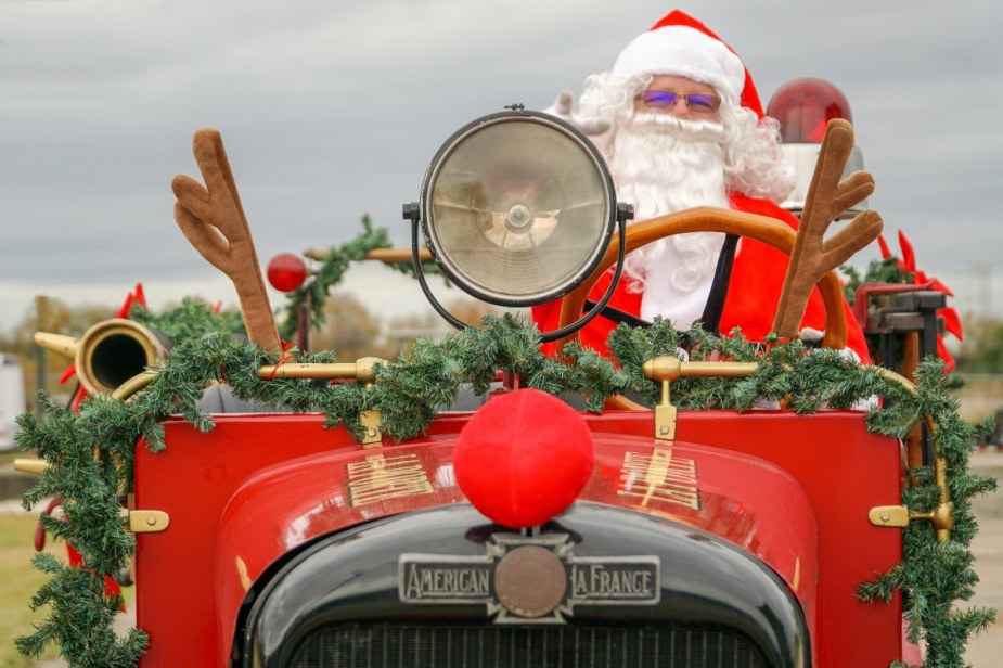 Santa Claus driving a red vintage car, highlighting who is faster, Santa or Elon Musk in a Tesla