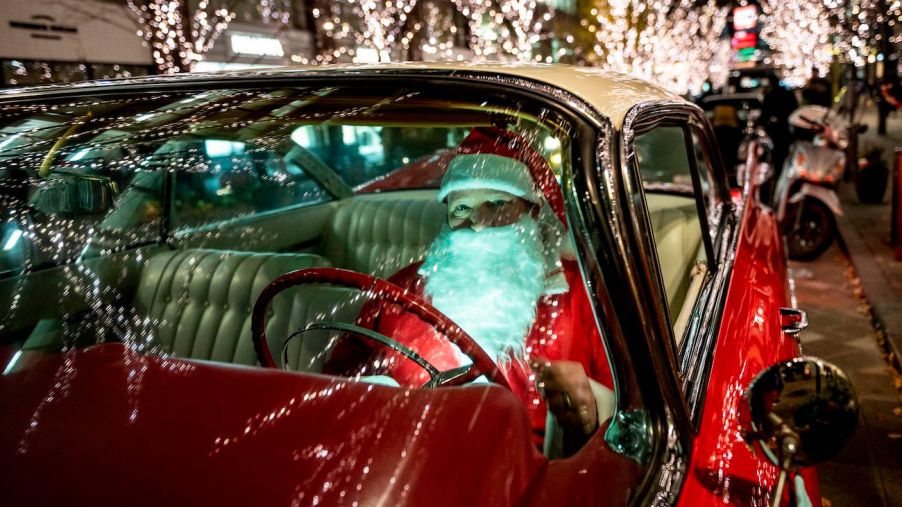 A man dressed as Santa Claus driving a car.