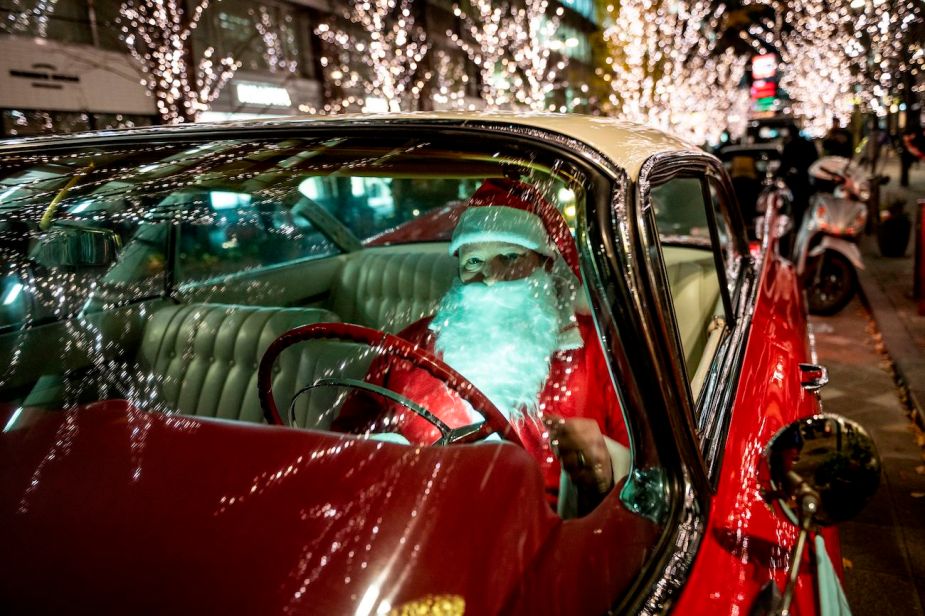 A man dressed as Santa Claus driving a car.