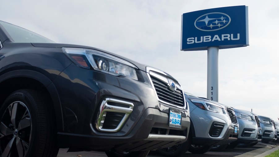 A row of Subarus under a dealership sign with the brand's name.