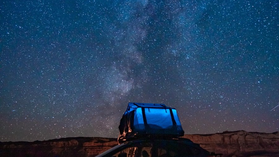 Promo photo of a Subaru car parked in a field beneath a bright night sky full of stars.