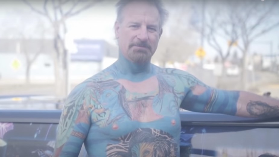 Tattooed “Mr. Avatar” man standing in front of his Avatar-themed pickup truck
