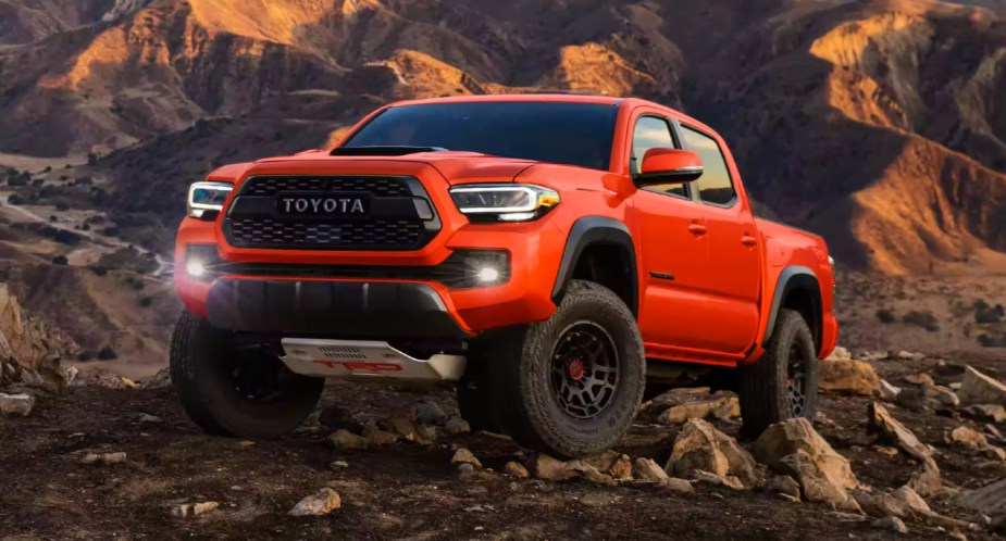 A red 2023 Toyota Tacoma midsize pickup truck is parked off-road. 