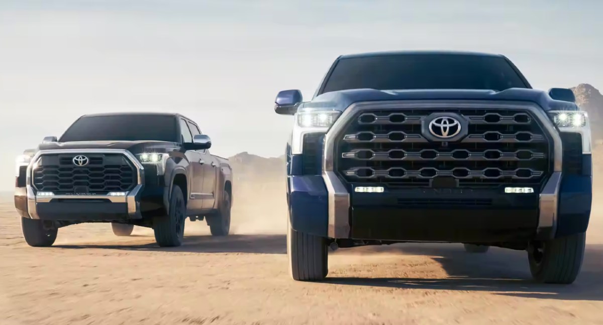 Two Toyota Tundras driving on a dirty road.