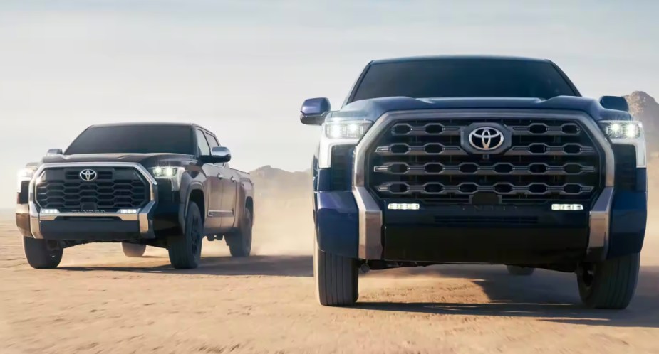 A black (L) and blue (R) Toyota Tundra drives off-road. 
