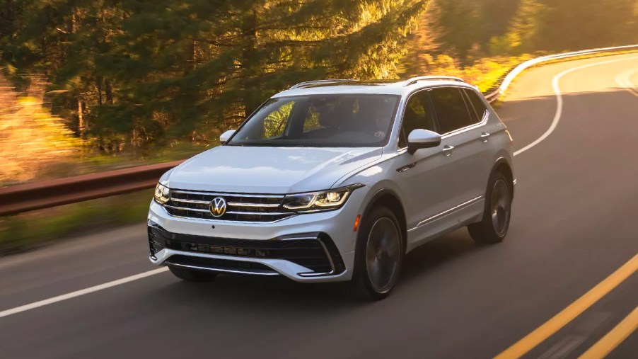 A white 2023 Volkswagen Tiguan small SUV is driving on the road.