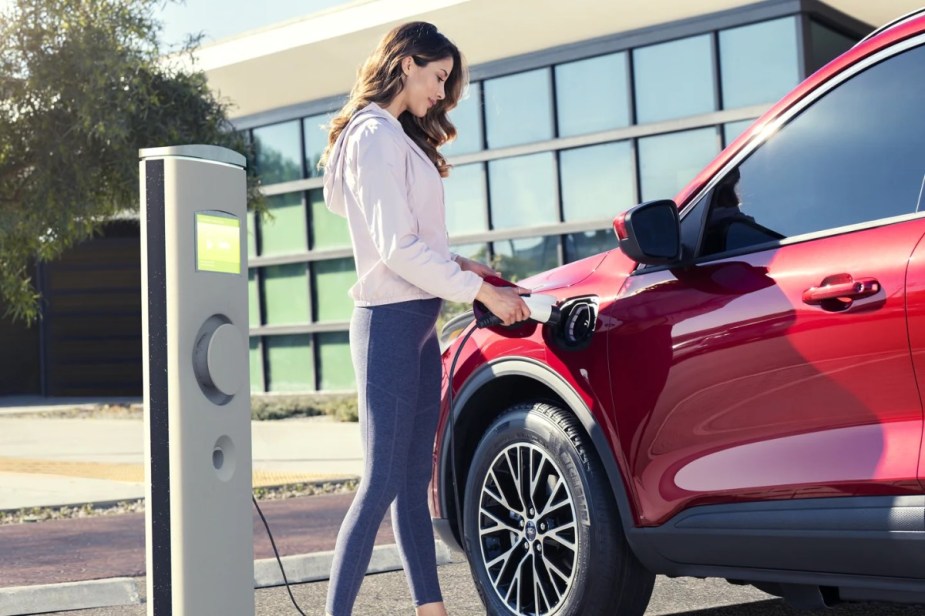 Woman charging a red 2023 Ford Escape Plug-In Hybrid, the 2023 Ford SUV with the highest fuel economy