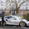 A car wash man cleans a luxury Porsche.