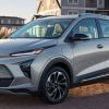 A silver-gray 2023 Chevy Bolt EUV compact electric SUV model parked outside of a home on a cobblestone road