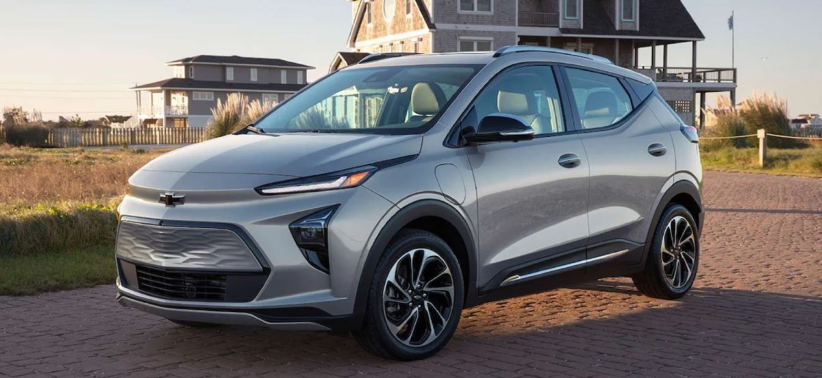 A silver-gray 2023 Chevy Bolt EUV compact electric SUV model parked outside of a home on a cobblestone road