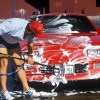 A man washing his red car