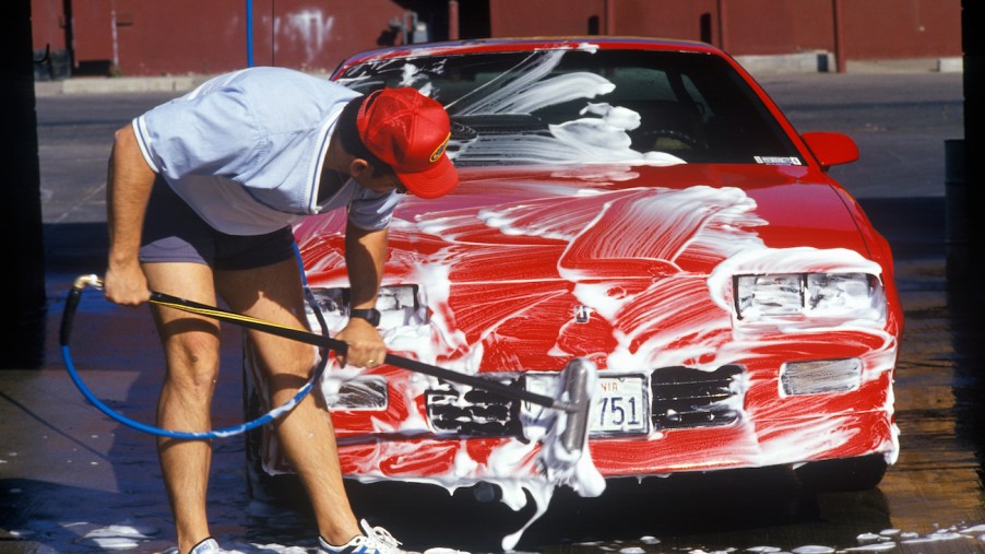 A man washing his red car