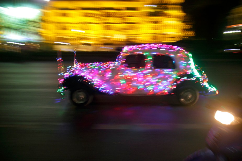 An old classic car covered in Christmas lights.