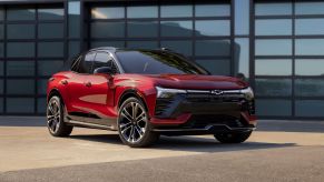A red 2024 Chevrolet Chevy Blazer EV all-electric compact SUV model parked outside a reflective garage door