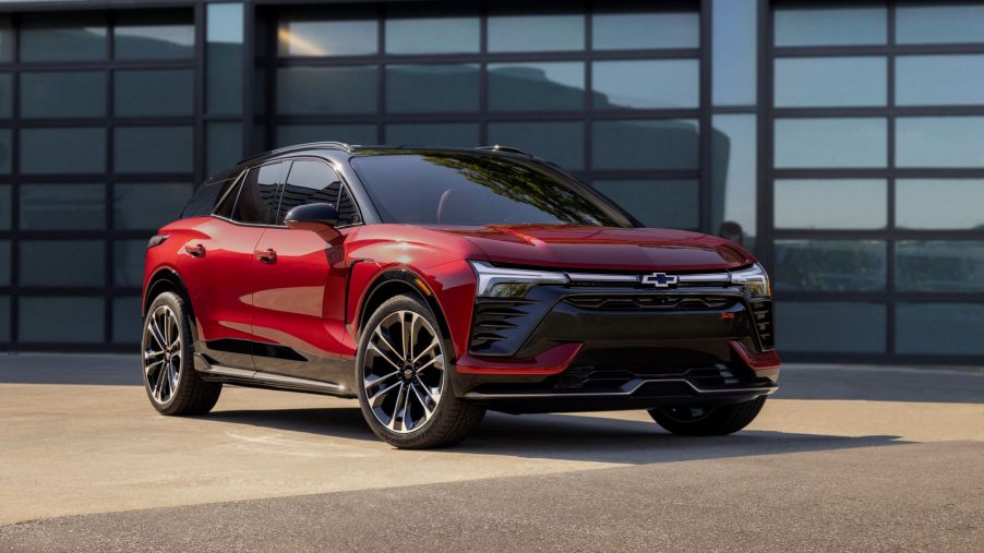A red 2024 Chevrolet Chevy Blazer EV all-electric compact SUV model parked outside a reflective garage door
